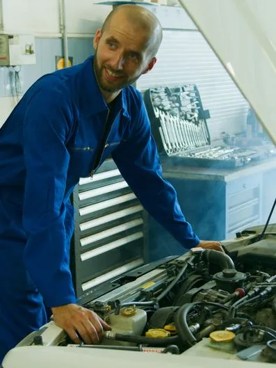Des mécaniciens examinent un moteur, capot ouvert, dans l'atelier de la rédaction.