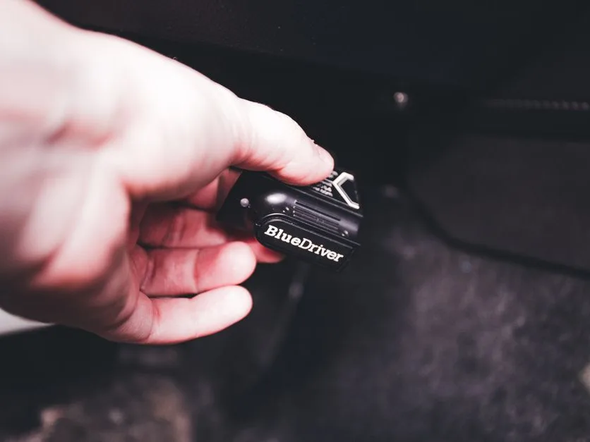 Un technicien relie une valise de diagnostic au calculateur d'une voiture en atelier.