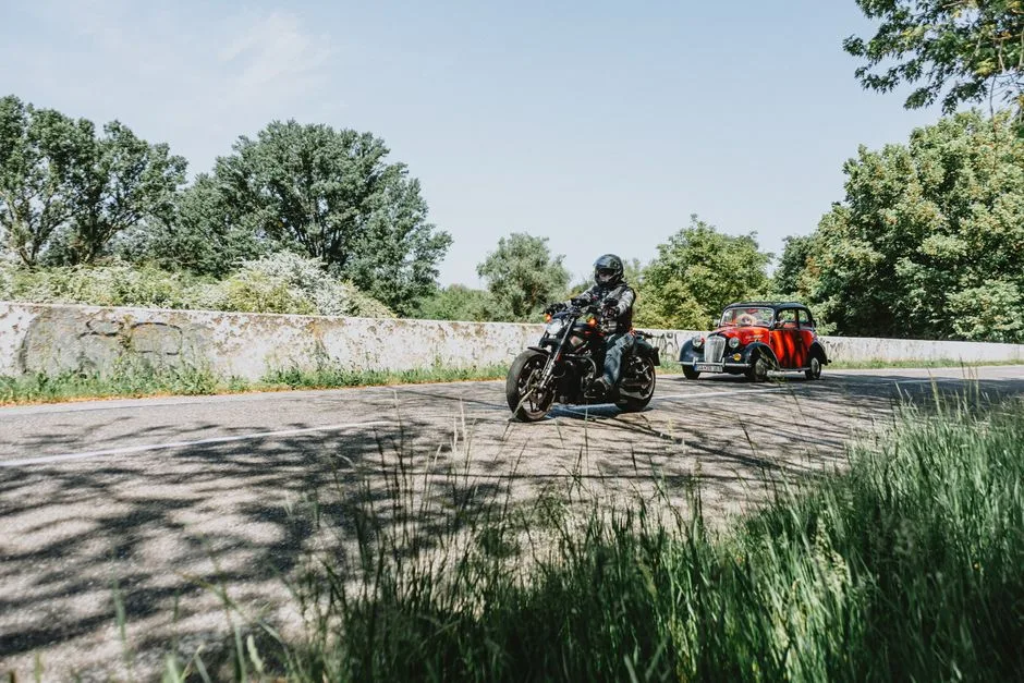 Une moto et une voiture se croisent sur une route de campagne.